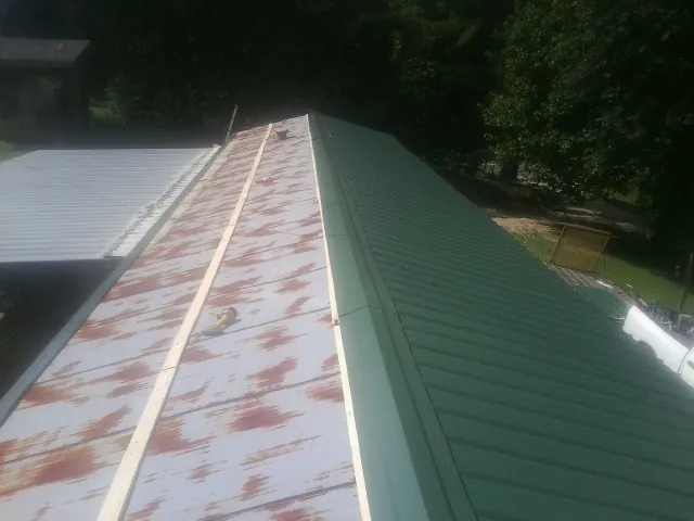 Old rusted panels beside newly installed green metal roofing — Wind Damage Roof Repair by Roofing Brothers in Springfield